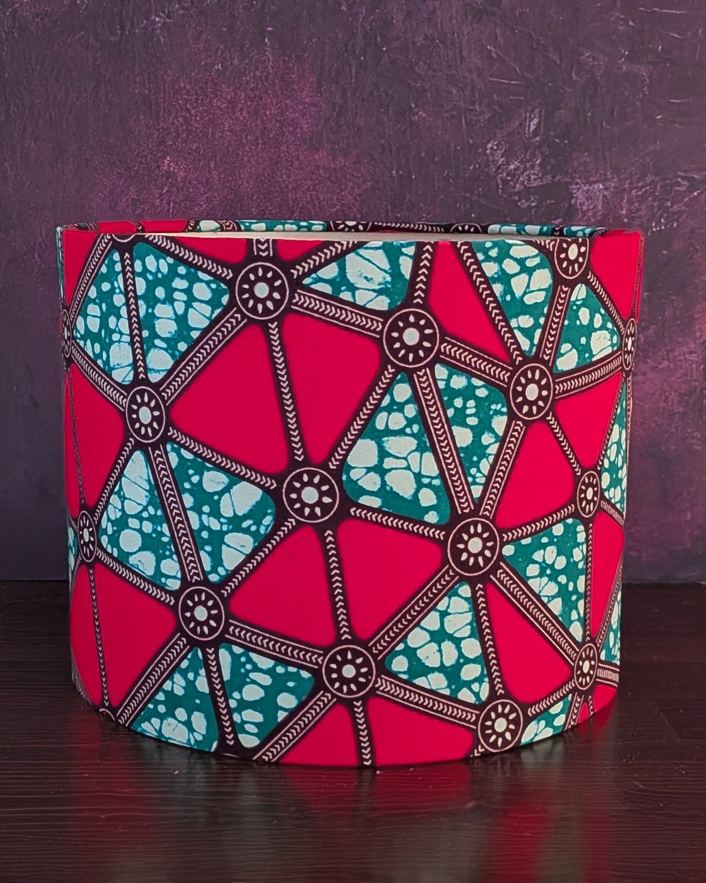 Colorful geometric African patterned lampshade on a dark surface with a purple background