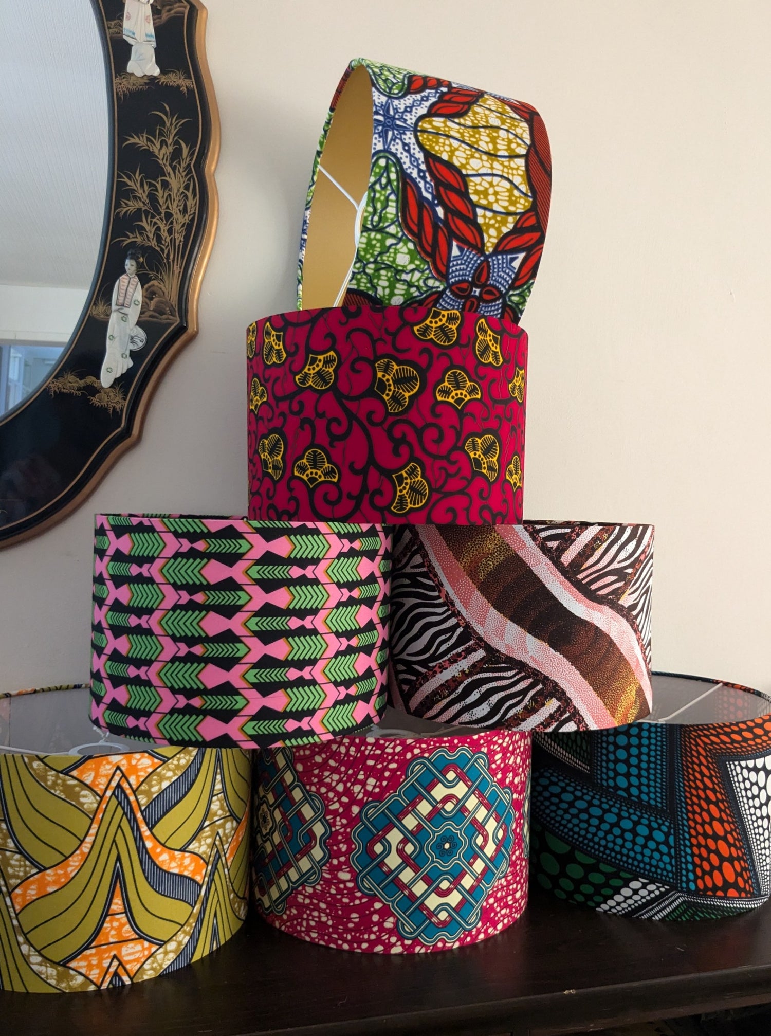 A couple of colourful African patterned drum lampshades. The bigger one is in an orange colourway & the smaller one is mainly pink.