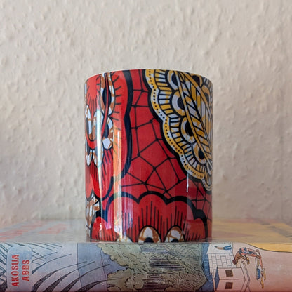 Colorful cylindrical mug with a wax print pattern on top of books against a textured wall.