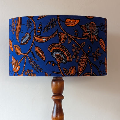 Lampshade with blue and orange floral botanical pattern on a wooden lamp base against a white background