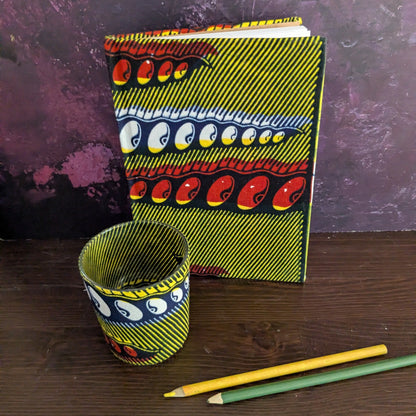Colorful notebook and candle holder with abstract designs on a wooden surface