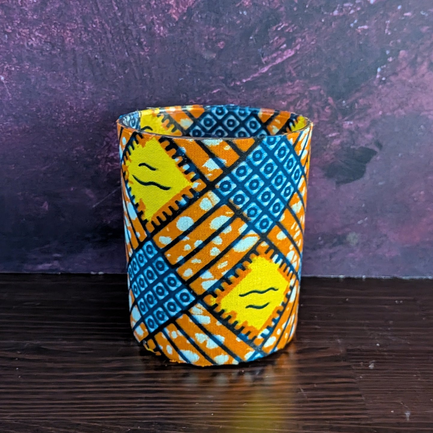 Decorative candle holder with blue and orange pattern on a dark surface