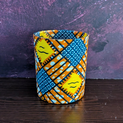 Decorative candle holder with blue and orange pattern on a dark surface