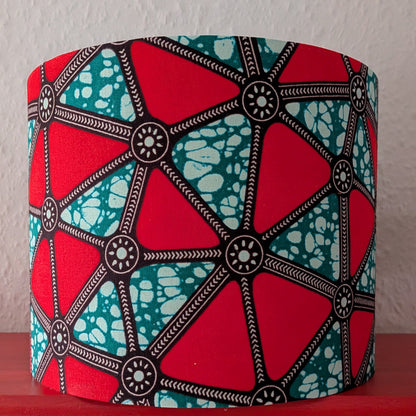 Colorful drum lampshade with geometric patterned triangles on a red surface