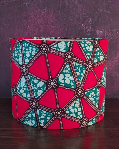Colorful geometric African patterned lampshade on a dark surface with a purple background